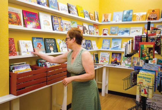 Carol Price of BookPeople of Moscow shelves books. Photo by Geoff Crimmins of Daily News