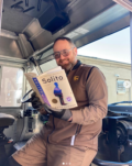 UPS driver, Joe, leans against his truck dashboard reading "Solito."