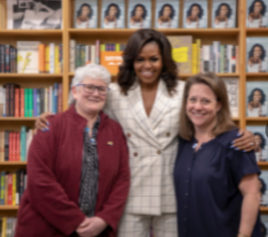 Sally McPherson, Michelle Obama, and Kim Bissell pose in front of bookshelves featuring "Becoming" at Broadway Books in Portland, OR in 2019